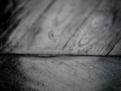 Close-up of a dumbbell on a dark wooden floor.